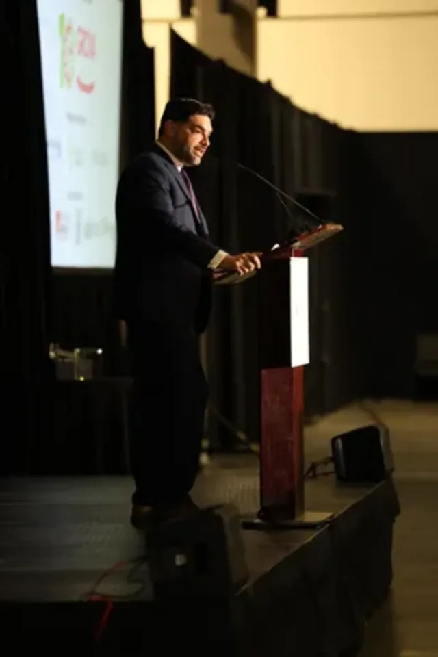 Eddie Gonzalez Loumiet on stage delivering remarks at a public speaking event in Tallahassee